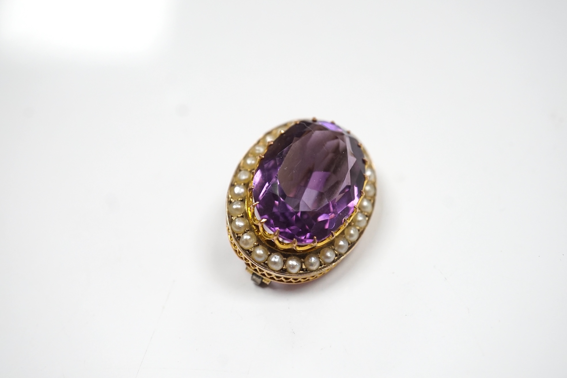 A mid 20th century 9ct and single stone oval cut amethyst set pendant brooch, with seed pearl border, 24mm, gross weight 4.8 grams. Condition - fair to good